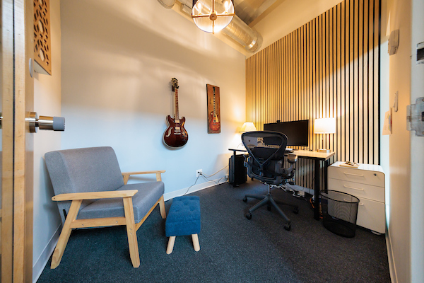 Private office with a guitar on the wall and a wood-slat accent wall at Platform Coworking